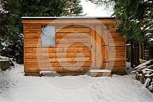 Waney edge wooded garden shed covered in snow after heavy snowfall