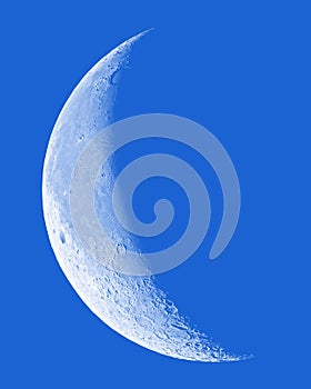 Waning Crescent Moon with crater detail on blue sky