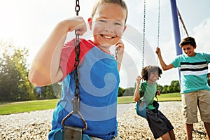 Wanna see my swinging skills. Portrait of a young boy playing on a swing at the park with his friends.