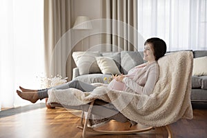 Peaceful young woman expecting mother recline on comfy rocking chair photo