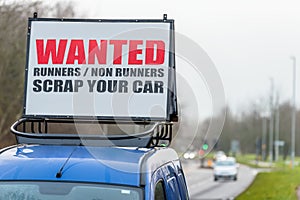 Wanted Runners Non Runners Scrap Your Car sign on car roof next to UK motorway photo