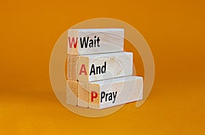 WAP, Wait and pray symbol. Wooden blocks with concept words `WAP, Wait and pray`. Beautiful orange background, copy space.