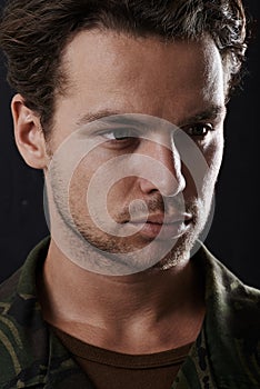 War changes a man. Cropped view of a man in fatigues looking serious against a black background.