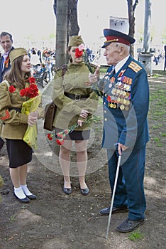 War veteran man portrait. He receives flowers from young women