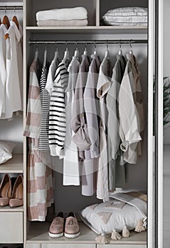 Wardrobe closet with different stylish clothes, shoes and home stuff in room