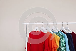 Wardrobe rack with different bright clothes on light background.