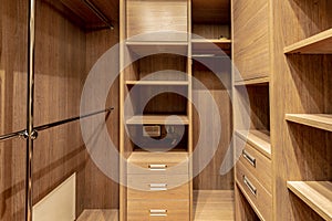 Wardrobe room interior with wooden cabinets and shelving.