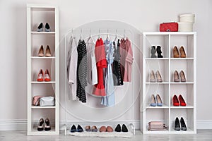 Wardrobe shelves with different stylish shoes and clothes indoors