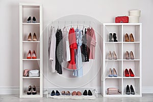 Wardrobe shelves with different stylish shoes and clothes indoors photo
