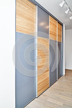 Wardrobe with sliding doors of natural oak timber and blank grey parts