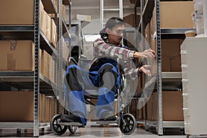 Warehouse asian package handler in wheelchair searching cardboard box