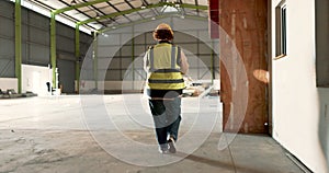 Warehouse, back of woman and engineer walking at empty industrial plant, manufacturing production or construction