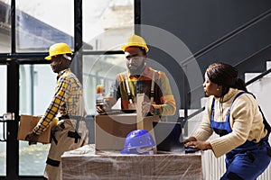 Warehouse employees checking orders on laptop and packing parcels