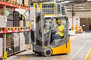 Warehouse forklift driver controlling shipping order. Warehouse worker preparing products for shipmennt, delivery