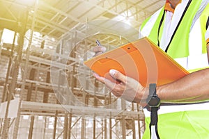 Warehouse inventory management. Warehouse worker holding clipboard his inspecting the products on tall shelves warehouse storage