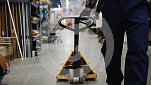 Warehouse loader dragging hand pallet truck or manual forklift with the shipment pallet in a construction store