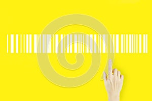 Warehouse and logistics concept. Young woman`s hand pointing finger with hologram Bar Code Price Tag on yellow background.