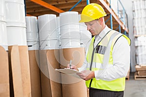 Warehouse manager checking his list on clipboard