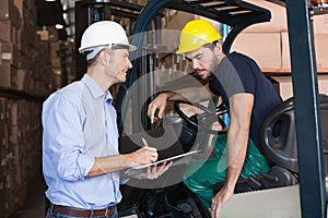 Warehouse manager talking with forklift driver photo