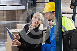 Warehouse manager talking with forklift driver