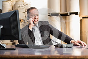 Warehouse manager using telephone and laptop