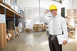 Warehouse manager wearing hard hat holding clipboard