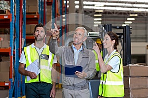 Warehouse manager and workers discussing with clipboard