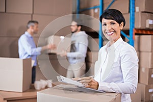 Warehouse manager writing on clipboard