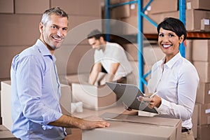 Warehouse manager writing on clipboard talking to colleague