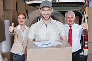 Warehouse managers and delivery driver smiling at camera