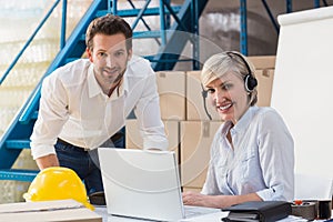 Warehouse managers using laptop and wearing headset
