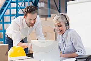 Warehouse managers using laptop and wearing headset