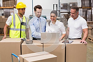 Warehouse managers and worker looking at laptop