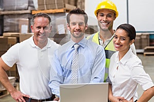 Warehouse managers and worker smiling at camera