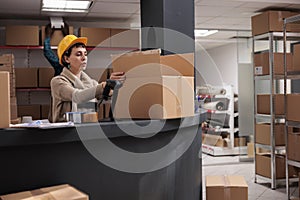 Warehouse operative putting products in box at counter desk