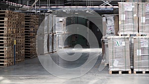 Warehouse with racks and shelves, filled with cardboard boxes, wrapped in foil on wooden pallets. Clip. Large and light