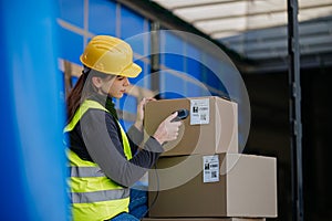 Warehouse receiver kneeling inside of truck in cargo area, trailer, barcode scanning delivered items. Receiving clerk