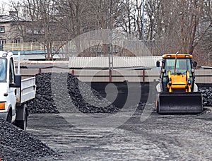 Warehouse for retail sale of coal to the population with a loading excavator of yellow color.Trade in natural resources and minera photo