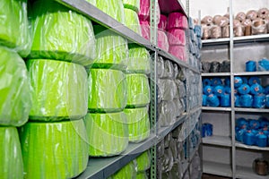 Warehouse with skeins of colored threads on shelves of high racks.