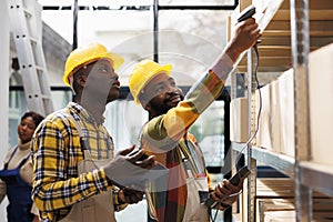 Warehouse smiling colleagues scanning cardboard box barcode and chatting