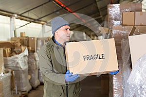 Warehouse worker carrying boxes on racks in in warehouse