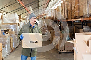 Warehouse worker carrying boxes on racks in in warehouse