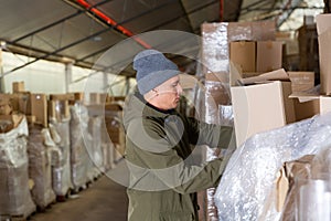 Warehouse worker carrying boxes on racks in in warehouse