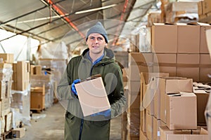 Warehouse worker carrying boxes on racks in in warehouse