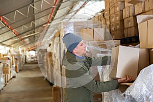 Warehouse worker carrying boxes on racks in in warehouse