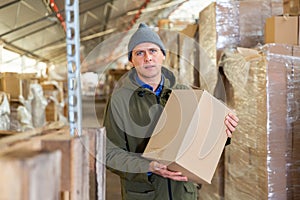 Warehouse worker carrying large box of goods in arehouse