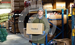 Warehouse worker carrying large box of goods in arehouse