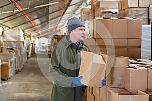 Warehouse worker carrying large box of goods in arehouse