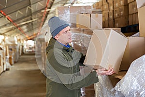 Warehouse worker carrying large box of goods in arehouse