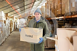 Warehouse worker carrying large box of goods in arehouse